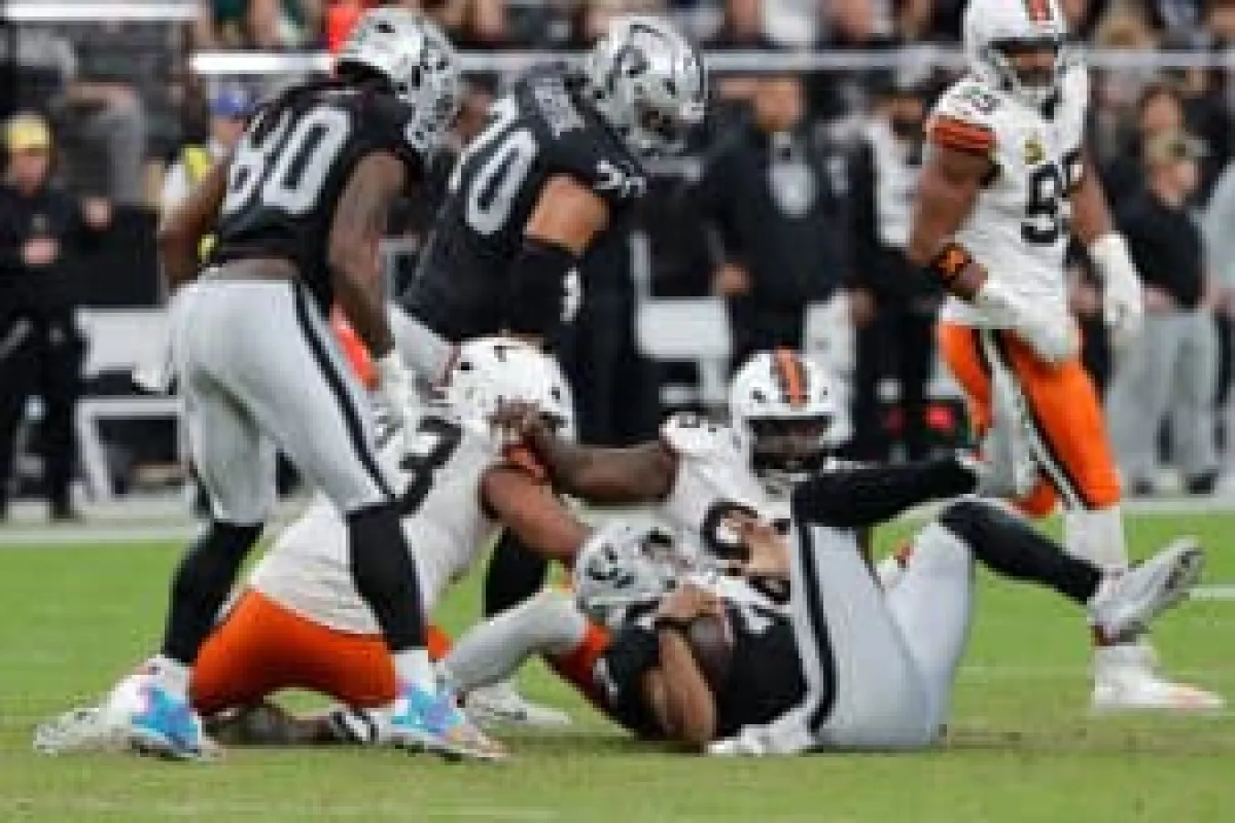 LAS VEGAS, NEVADA - NOVEMBER 23: Geno Smith #7 of the Las Vegas Raiders falls after being sacked by Maliek Collins #96 and Shelby Harris #93 of the Cleveland Browns during the second quarter of a game at Allegiant Stadium on November 23, 2025 in Las Vegas, Nevada.