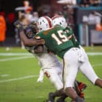 Louisville Cardinals quarterback Micale Cunningham (3) throws the ball and is tackled by Miami Hurricanes defensive lineman Gregory Rousseau (15) and Miami Hurricanes defensive lineman Jonathan Garvin (97) during the college football game between the Louisville Cardinals and the University of Miami Hurricanes on November 9, 2019 at the Hard Rock Stadium in Miami Gardens, Florida.