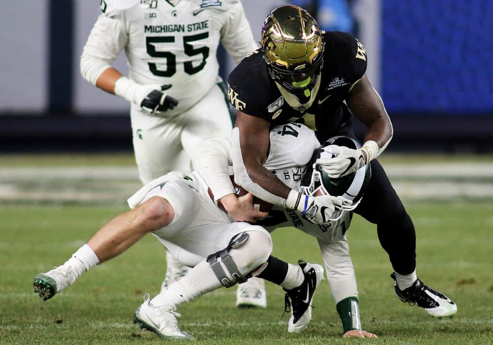 Wake Forest Demon Deacons defensive lineman Carlos Basham Jr. (9) takes down Michigan State Spartans quarterback Brian Lewerke (14) down for a sack during the 2019 Pinstripe Bowl between the Michigan State Spartans and the Wake Forest Demon Deacons on December 27, 2019, at Yankee Stadium in New York, NY.