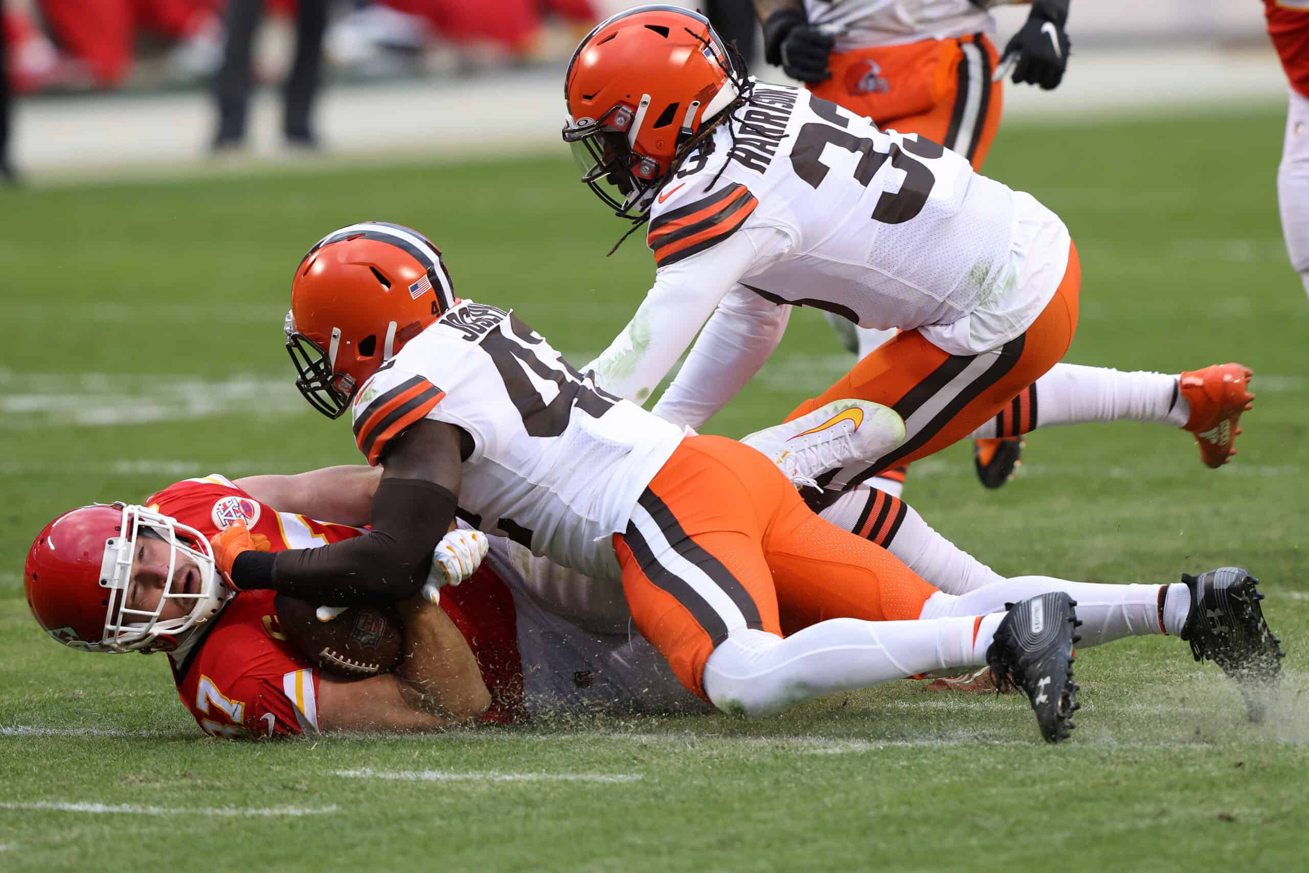 Tight end Travis Kelce #87 of the Kansas City Chiefs completes a pass over strong safety Karl Joseph #42 and strong safety Ronnie Harrison #33 of the Cleveland Browns during the third quarter at Arrowhead Stadium on January 17, 2021 in Kansas City, Missouri.