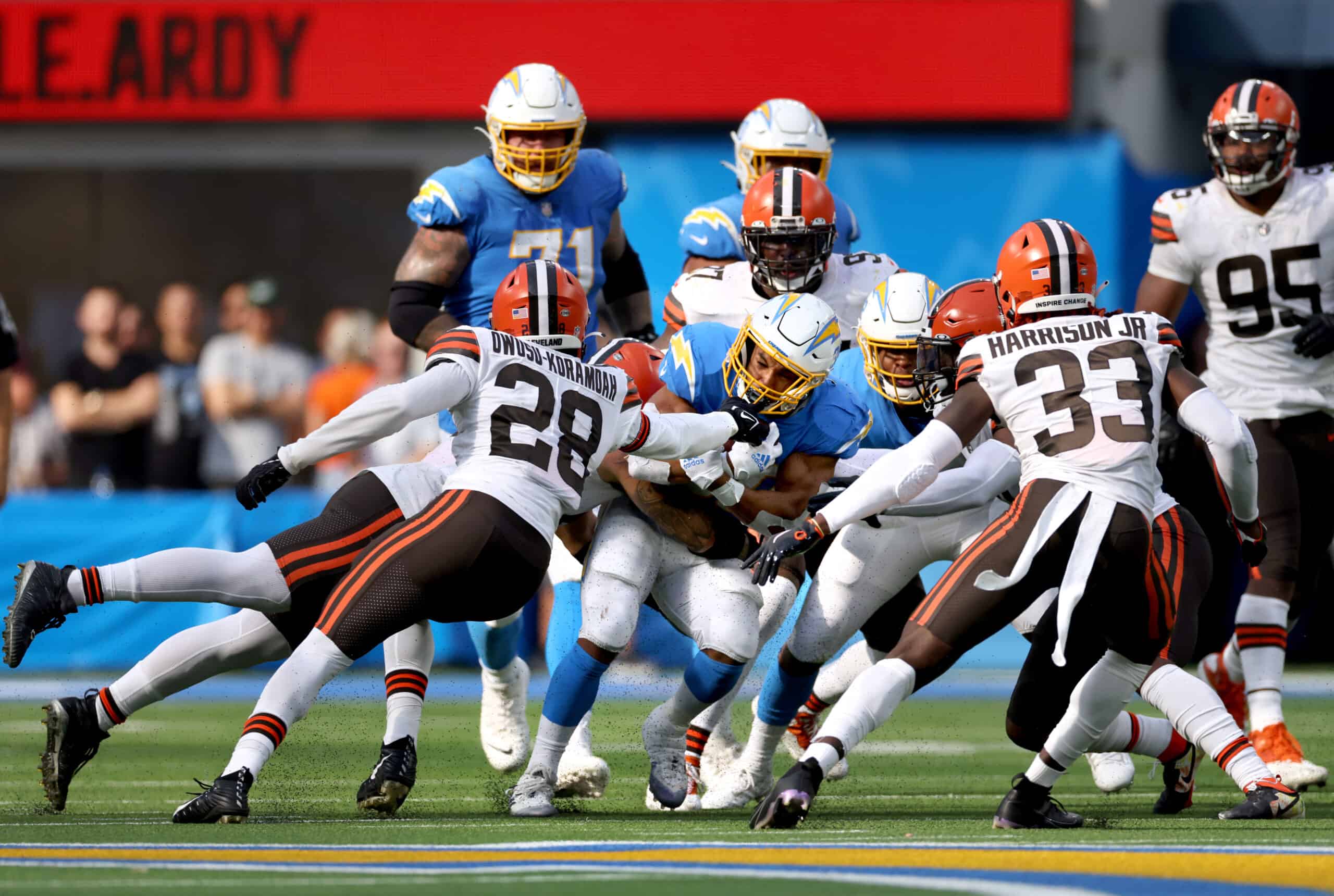 Austin Ekeler #30 of the Los Angeles Chargers runs the ball and is hit by Jeremiah Owusu-Koramoah #28, Sione Takitaki #44, and Ronnie Harrison #33 of the Cleveland Browns during the fourth quarter at SoFi Stadium on October 10, 2021 in Inglewood, California.