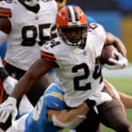 Nick Chubb #24 of the Cleveland Browns runs as he is tackled by Drue Tranquill #49 of the Los Angeles Chargers during a 49-42 loss to the Los Angeles Chargers at SoFi Stadium on October 10, 2021 in Inglewood, California.