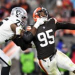 Myles Garrett #95 of the Cleveland Browns is tackled by Brandon Parker #75 of the Las Vegas Raiders in the fourth quarter of the game at FirstEnergy Stadium on December 20, 2021 in Cleveland, Ohio.