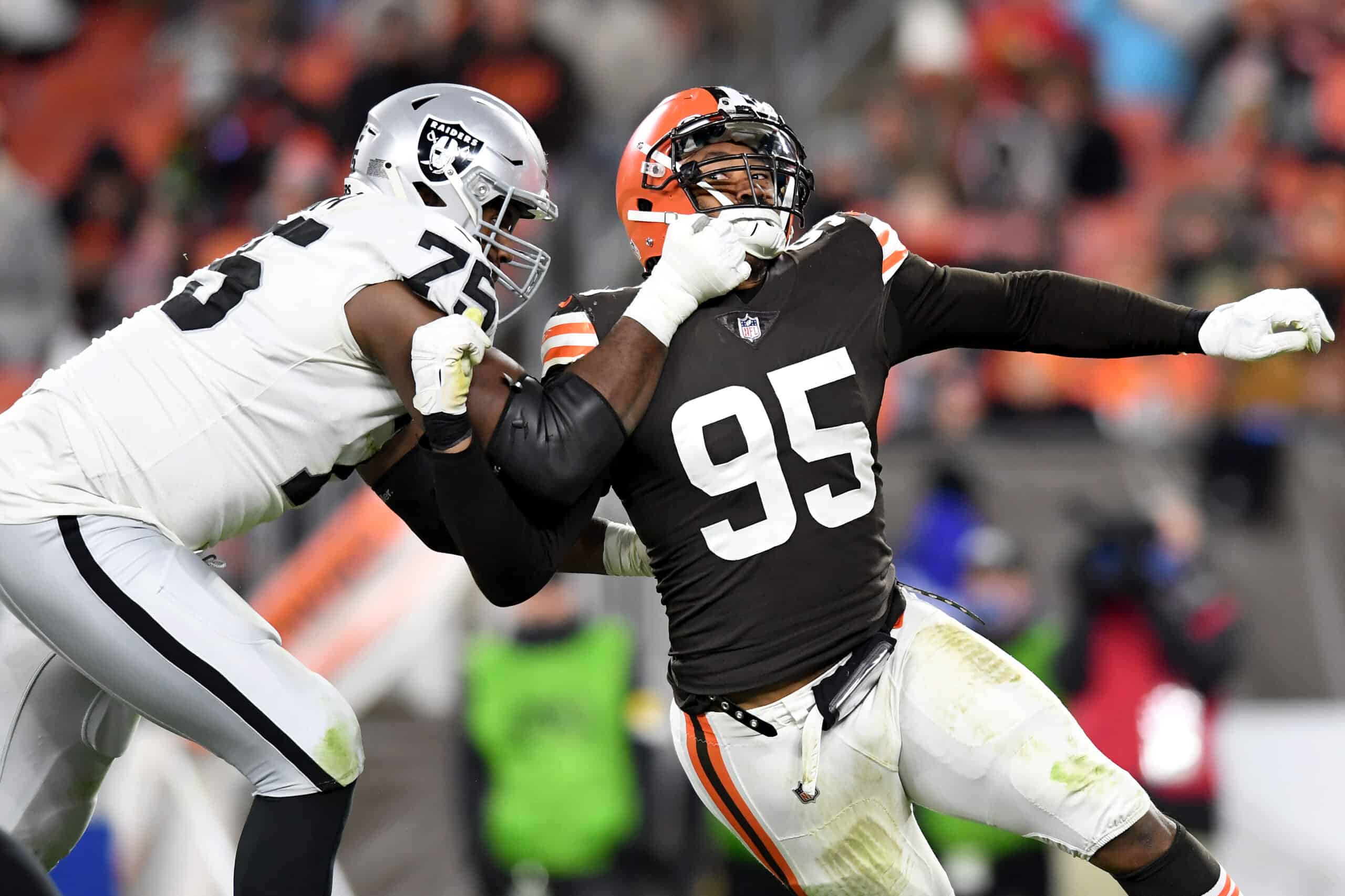 Myles Garrett #95 of the Cleveland Browns is tackled by Brandon Parker #75 of the Las Vegas Raiders in the fourth quarter of the game at FirstEnergy Stadium on December 20, 2021 in Cleveland, Ohio.