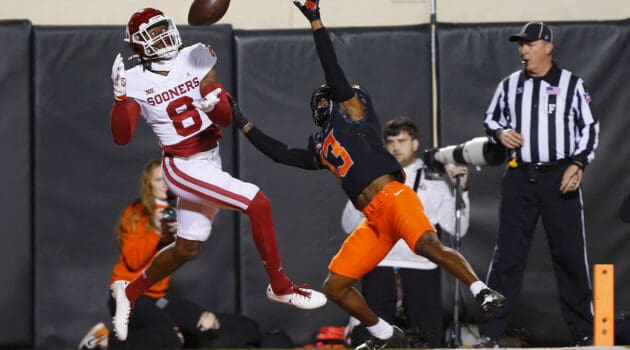 Wide receiver Michael Woods II #8 of the Oklahoma Sooners tries to catch a pass in the end zone but instead picks up a pass interference penalty against safety Thomas Harper #13 of the Oklahoma State Cowboys in the first quarter at Boone Pickens Stadium on November 27, 2021 in Stillwater, Oklahoma.