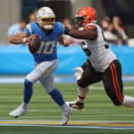 Justin Herbert #10 of the Los Angeles Chargers avoids a tackle by Jordan Elliott #96 of the Cleveland Browns during the first quarter at SoFi Stadium on October 10, 2021 in Inglewood, California.