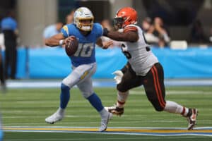 Justin Herbert #10 of the Los Angeles Chargers avoids a tackle by Jordan Elliott #96 of the Cleveland Browns during the first quarter at SoFi Stadium on October 10, 2021 in Inglewood, California.