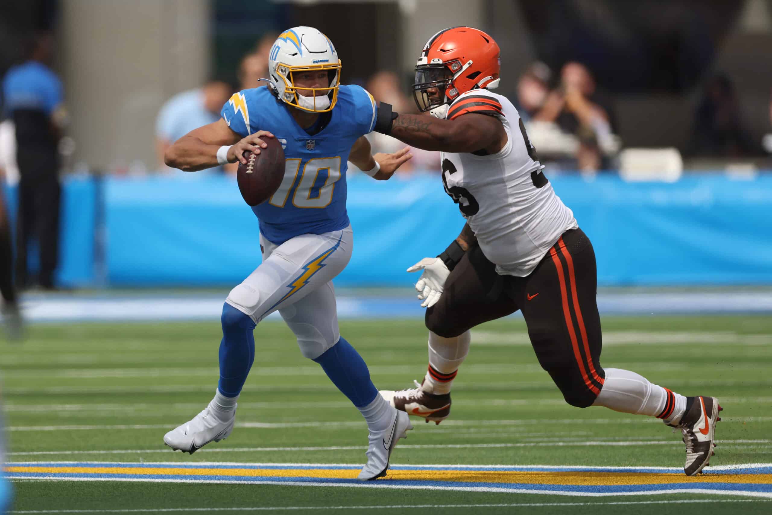 Justin Herbert #10 of the Los Angeles Chargers avoids a tackle by Jordan Elliott #96 of the Cleveland Browns during the first quarter at SoFi Stadium on October 10, 2021 in Inglewood, California. 