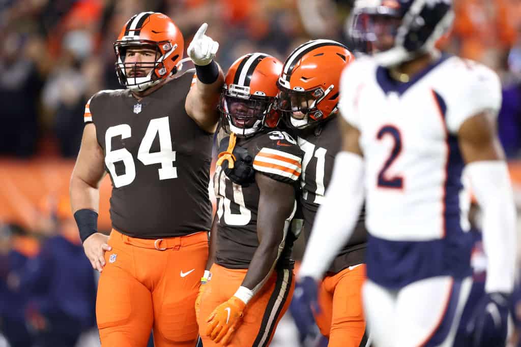 Center JC Tretter #64 and offensive tackle Jedrick Wills #71 celebrate with running back D'Ernest Johnson #30 of the Cleveland Browns after Johnson rushed for a first down late in the fourth quarter against the Denver Broncos at FirstEnergy Stadium on October 21, 2021 in Cleveland, Ohio.