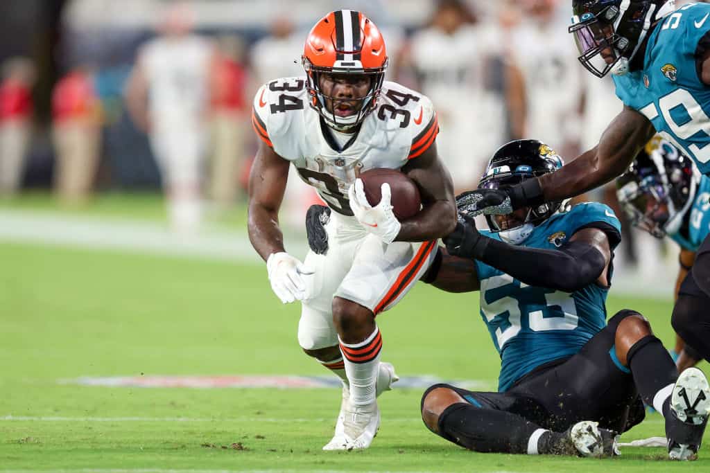 Jerome Ford #34 of the Cleveland Browns looks to break the tackle of Chapelle Russell #53 of the Jacksonville Jaguars during a football game at TIAA Bank Field on August 12, 2022 in Jacksonville, Florida.