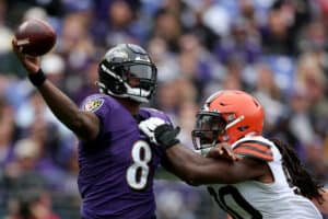 Quarterback Lamar Jackson #8 of the Baltimore Ravens gets off a pass while being pressured by defensive end Jadeveon Clowney #90 of the Cleveland Browns in the first half at M&T Bank Stadium on October 23, 2022 in Baltimore, Maryland.