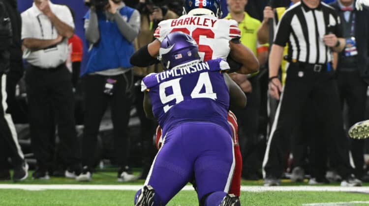 Dalvin Tomlinson #94 of the Minnesota Vikings tackles Saquon Barkley #26 of the New York Giants for a loss during the third quarter in the NFC Wild Card playoff game at U.S. Bank Stadium on January 15, 2023 in Minneapolis, Minnesota.