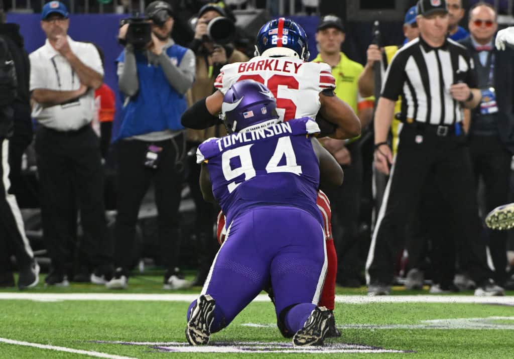 Dalvin Tomlinson #94 of the Minnesota Vikings tackles Saquon Barkley #26 of the New York Giants for a loss during the third quarter in the NFC Wild Card playoff game at U.S. Bank Stadium on January 15, 2023 in Minneapolis, Minnesota.