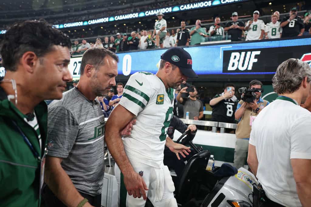 Quarterback Aaron Rodgers #8 of the New York Jets is helped off the field after an injury during the first quarter of the NFL game against the Buffalo Bills at MetLife Stadium on September 11, 2023 in East Rutherford, New Jersey.