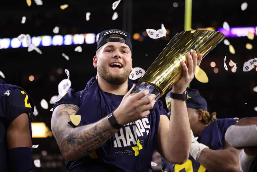 Zak Zinter #65 of the Michigan Wolverines holds the national championship trophy after defeating the Washington Huskies during the 2024 CFP National Championship game at NRG Stadium on January 08, 2024 in Houston, Texas. Michigan defeated Washington 34-13.