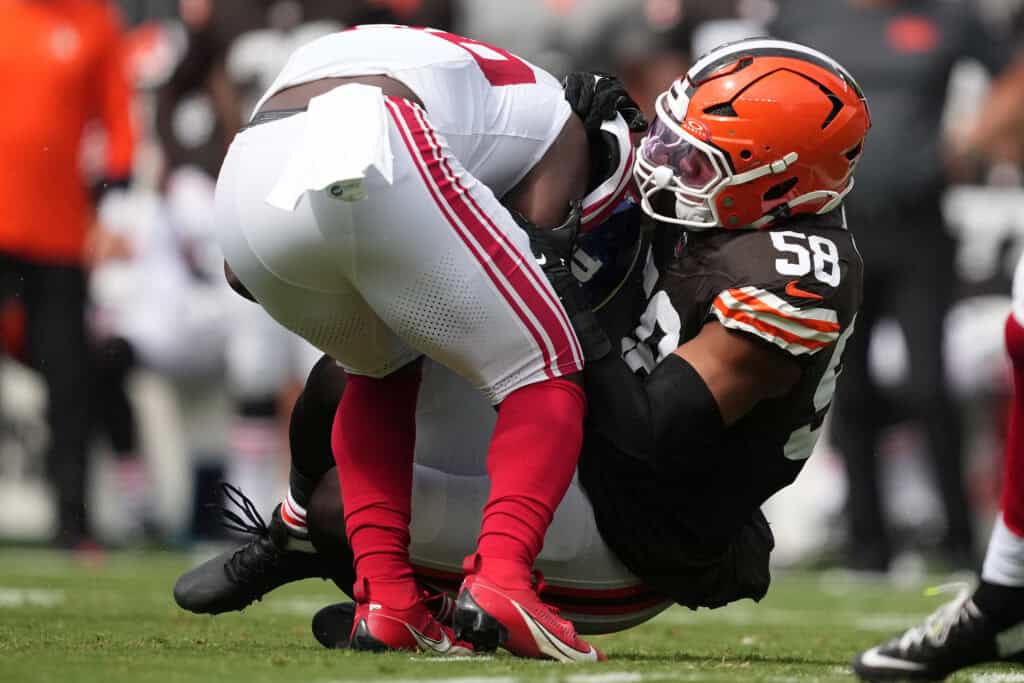 CLEVELAND, OHIO - SEPTEMBER 22: Devin Singletary #26 of the New York Giants is tackled by Jordan Hicks #58 of the Cleveland Browns during the first quarter at Cleveland Browns Stadium on September 22, 2024 in Cleveland, Ohio.