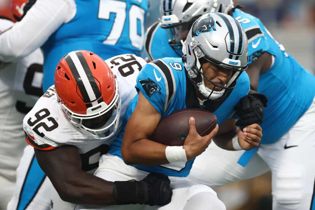 CHARLOTTE, NORTH CAROLINA - AUGUST 08: Quarterback Bryce Young #9 of the Carolina Panthers is tackled by defensive end Sam Kamara #92 of the Cleveland Browns in the first half during the NFL Preseason 2025 game at Bank of America Stadium on August 08, 2025 in Charlotte, North Carolina.