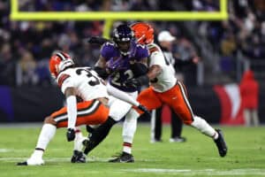 BALTIMORE, MARYLAND - JANUARY 04: Derrick Henry #22 of the Baltimore Ravens runs with the ball while defended by Ronnie Hickman #33 of the Cleveland Browns during the second quarter at M&T Bank Stadium on January 04, 2025 in Baltimore, Maryland.