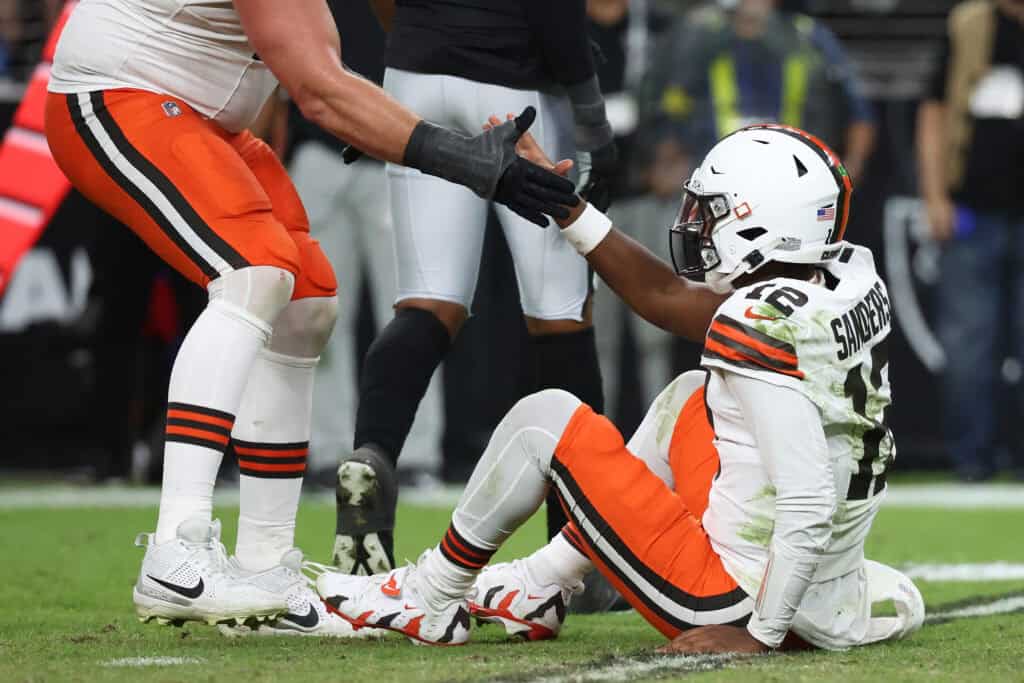 LAS VEGAS, NEVADA - NOVEMBER 23: Shedeur Sanders #12 is helped up by Wyatt Teller #77 of the Cleveland Browns in the third quarter against the Las Vegas Raiders at Allegiant Stadium on November 23, 2025 in Las Vegas, Nevada.