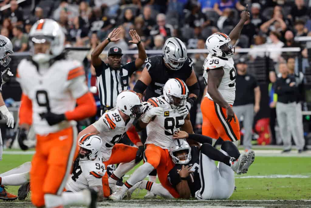 LAS VEGAS, NEVADA - NOVEMBER 23: Geno Smith #7 of the Las Vegas Raiders falls after being tackled by Cameron Thomas #99, Myles Garrett #95 and Maliek Collins #96 in the fourth quarter of a game at Allegiant Stadium on November 23, 2025 in Las Vegas, Nevada.