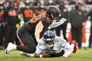 CLEVELAND, OHIO - DECEMBER 07: Carson Schwesinger #49 of the Cleveland Browns tackles Cam Ward #1 of the Tennessee Titans during the first quarter at Huntington Bank Field on December 07, 2025 in Cleveland, Ohio.