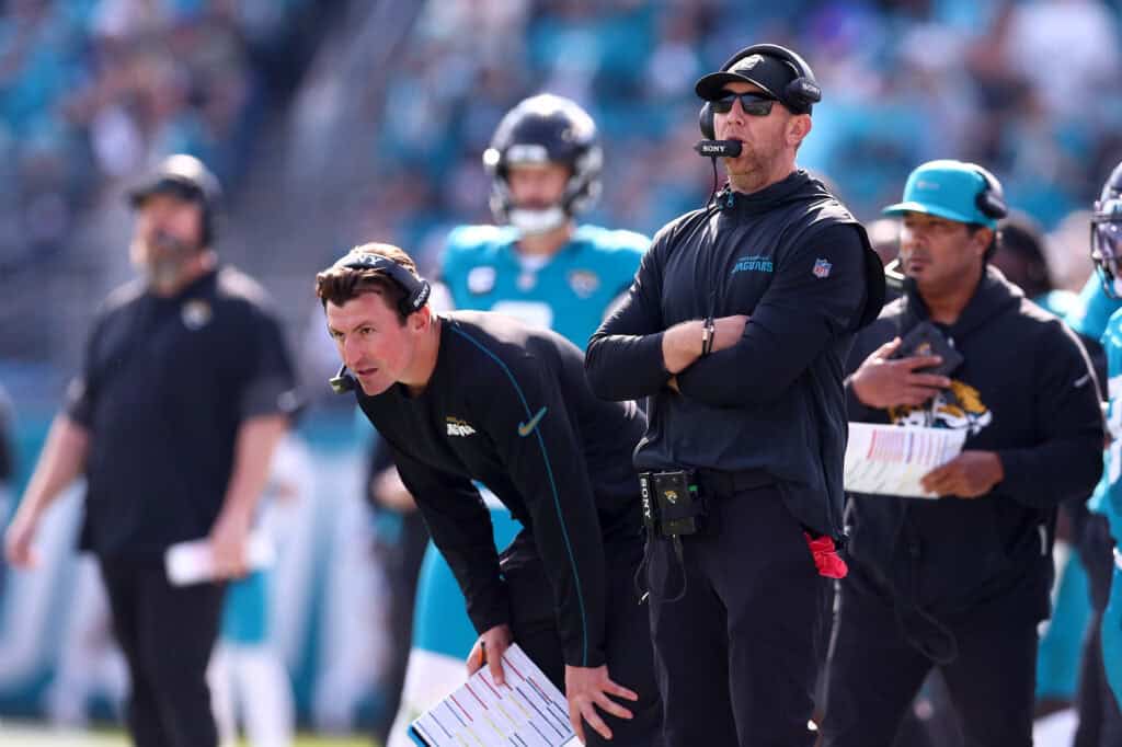 JACKSONVILLE, FLORIDA - JANUARY 11: (R-L) Head coach Liam Coen and offensive coordinator Grant Udinski of the Jacksonville Jaguars look on during the second quarter in the AFC Wild Card Playoff game at EverBank Stadium on January 11, 2026 in Jacksonville, Florida.