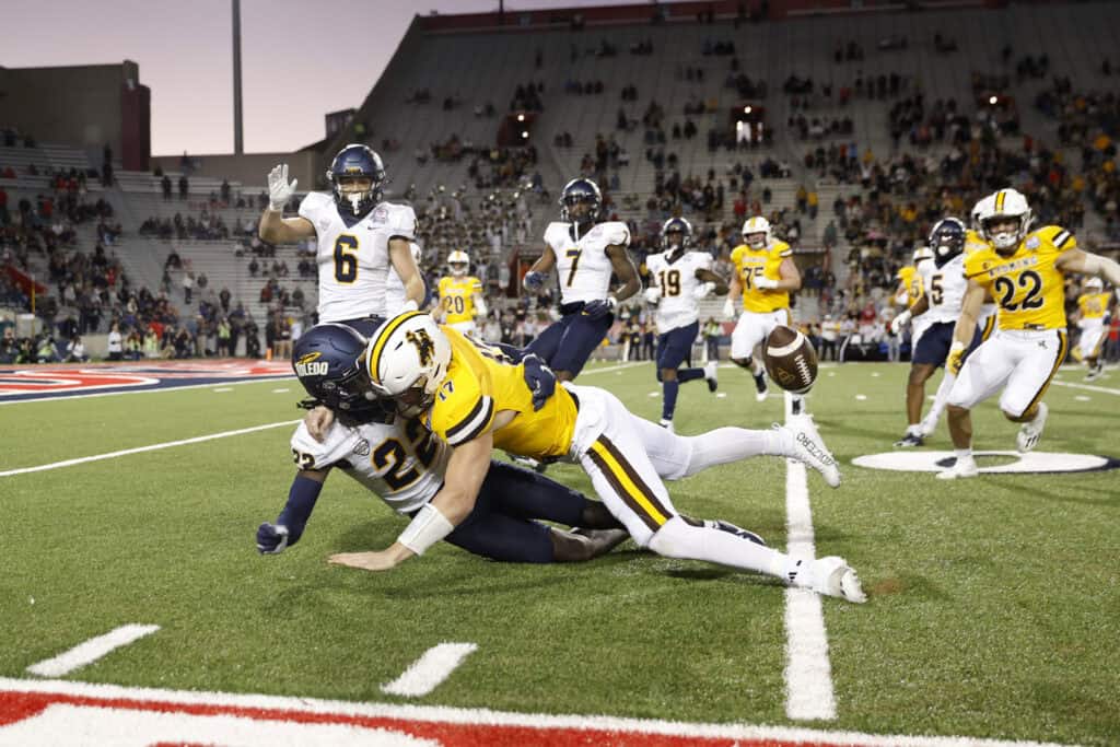 TUCSON, ARIZONA - DECEMBER 30: Quarterback Evan Svoboda #17 of the Wyoming Cowboys (C) fumbles after being hit by safety Emmanuel McNeil-Warren #22 of the Toledo Rockets during the second half of the Barstool Sports Arizona Bowl at Arizona Stadium on December 30, 2023 in Tucson, Arizona.