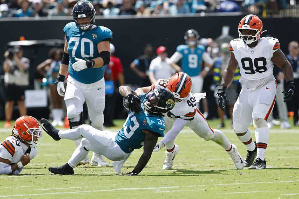 JACKSONVILLE, FLORIDA - SEPTEMBER 13: Bhayshul Tuten #33 of the Jacksonville Jaguars is tackled by Carson Schwesinger #49 of the Cleveland Browns during the first half of the game at EverBank Stadium on September 13, 2026 in Jacksonville, Florida.