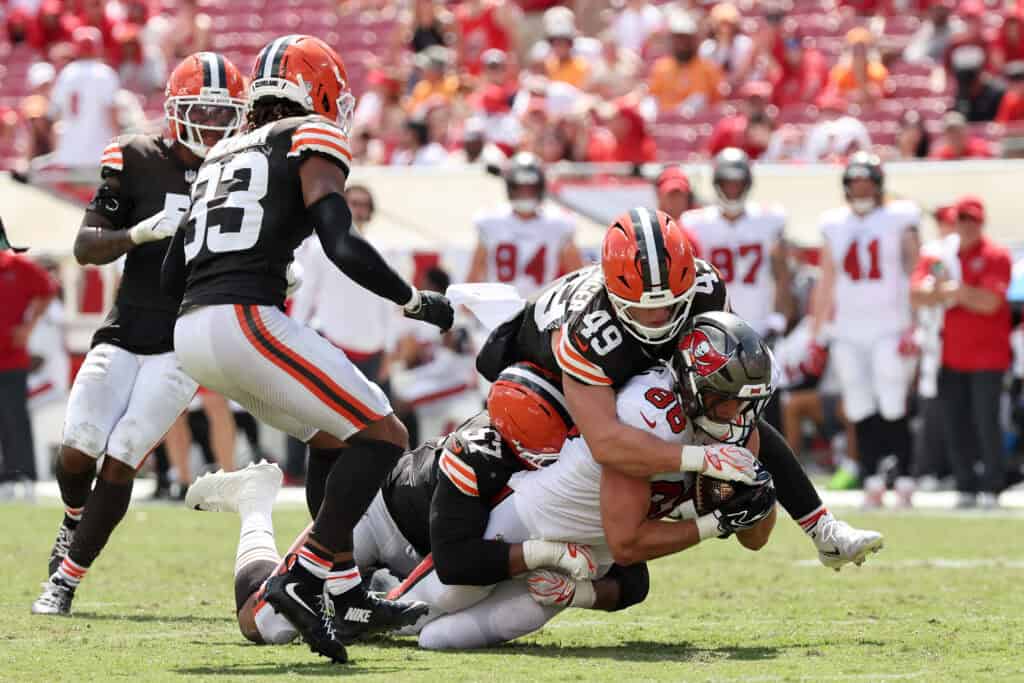 TAMPA, FLORIDA - SEPTEMBER 20: Cade Otton #88 of the Tampa Bay Buccaneers catches a ball and is tackled by Carson Schwesinger #49 of the Cleveland Browns and Isaiah McGuire #57 during the third quarter of the game at Raymond James Stadium on September 20, 2026 in Tampa, Florida.