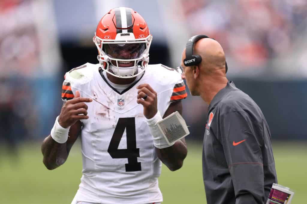 CHICAGO, ILLINOIS - AUGUST 15: Deshaun Watson #4 of the Cleveland Browns speaks with quarterback coach Mike Bajakian of the Cleveland Browns during the first quarter of a preseason game against the Chicago Bears at Soldier Field on August 15, 2026 in Chicago, Illinois.